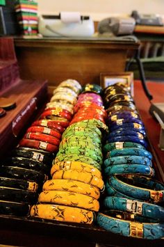 many bracelets are lined up in a row on a wooden table next to a computer keyboard