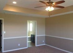 an empty room with a ceiling fan and carpeted floor in front of the door