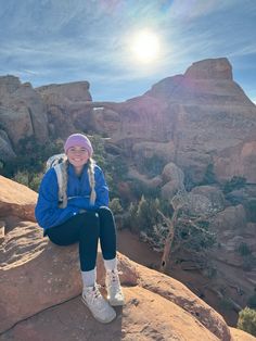 a woman sitting on top of a large rock