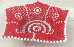 a red and white beaded object sitting on top of a table