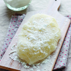 a wooden cutting board topped with dough on top of a table