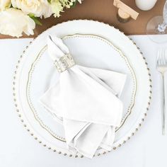 a place setting with white napkins and silverware