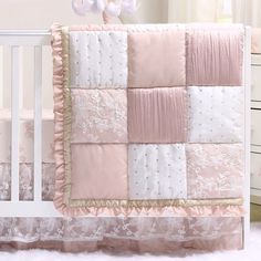 a baby crib with a pink and white quilt