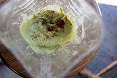 a blender filled with green liquid on top of a wooden table