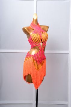 a mannequin wearing an orange and pink dress with fringes on it's chest