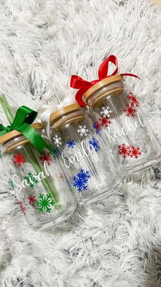 three glass jars with snowflakes and bows are sitting on a white furnishing