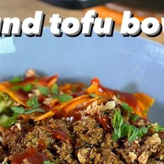 a blue bowl filled with meat and vegetables on top of a wooden table next to the words grand tofu bowl