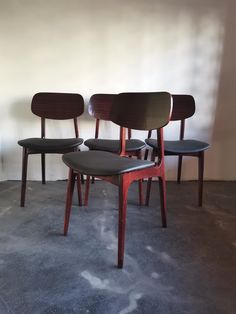 four chairs sitting side by side in a room with no one on the chair and two behind them