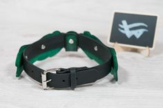 a black and green leather belt next to a small wooden sign with an arrow on it