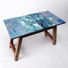 a glass table with wooden legs and blue paint on the top, against a white background