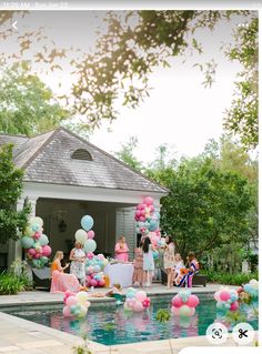 a group of people standing around a pool filled with balloons