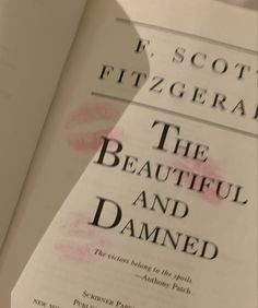 an open book with pink ink on it and the title in black is titled, the beautiful and damaged by scott fitzgerald