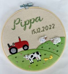 a small embroidered hoop with a farm scene and tractor on it that says pippa