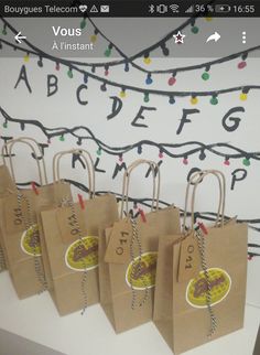 small brown paper bags are lined up on a table with string lights in the background