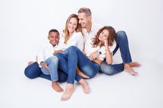 a family sitting on the floor posing for a photo with their arms around each other