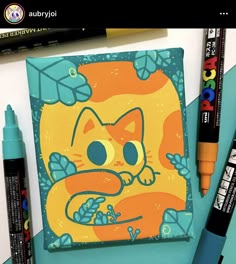 an orange cat is sitting on top of a notebook with markers and pens next to it