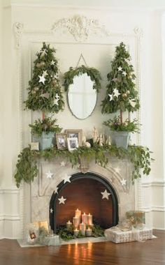 a fireplace decorated for christmas with greenery and candles