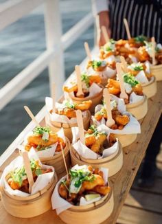 small trays filled with food sitting on top of a wooden table next to water