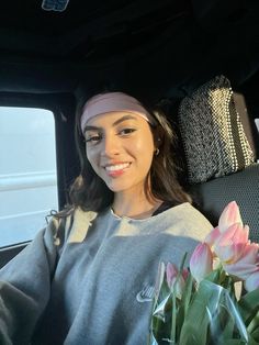 a woman sitting in the back seat of a car with tulips on her lap