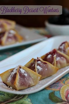 three desserts are sitting on a white plate with blueberries in the background and text overlay that reads blackberry desert wontons