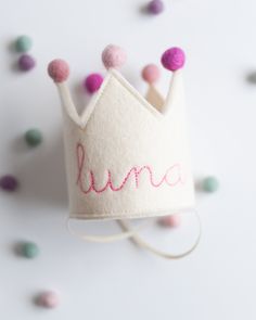 a crown with the word luna written on it and some pom - poms around it