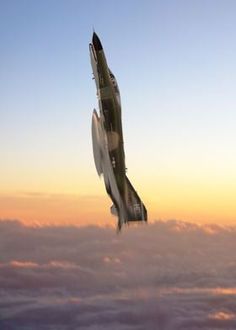 an airplane flying high above the clouds at sunset