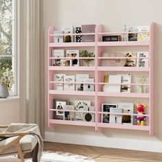 a pink book shelf with books on it in a room next to a chair and window