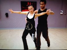 a man and woman are dancing on the dance floor in front of a tv screen