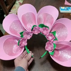 someone is making a pink flower wreath out of paper and some green ribbon on the top