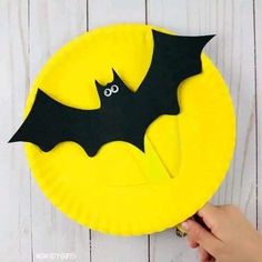 a paper plate with a bat cut out of it on top of a white wooden table