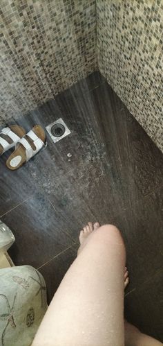 a person is standing in the shower with their feet up on the floor next to it