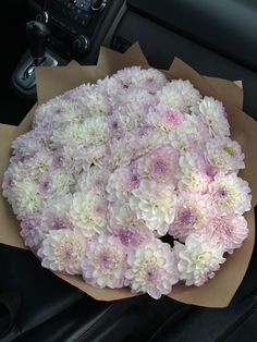 a bouquet of white and pink flowers sitting on top of a car dashboard