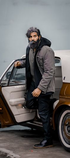 a man with a beard standing next to a car