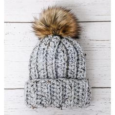 a gray knitted hat with a brown pom - pom sitting on top of it