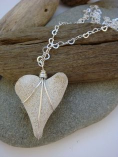 a white heart shaped pendant sitting on top of a rock