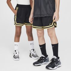 two young boys standing next to each other wearing black and white shorts with yellow trims