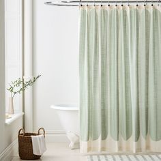 a white bath tub sitting next to a shower curtain with green and beige stripes on it