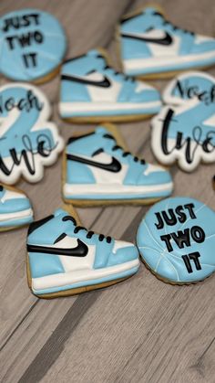 cookies decorated with nike shoes and just two it written in black on them are sitting on a wooden surface