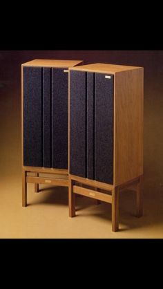 two wooden speakers sitting side by side on top of each other in front of a brown background