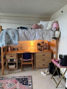 a dorm room with a desk, bed and other items on the floor in front of it