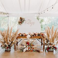 an arrangement of flowers and pamodia in front of a white sign that reads rileys