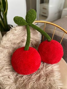 two knitted cherries sitting on top of a chair