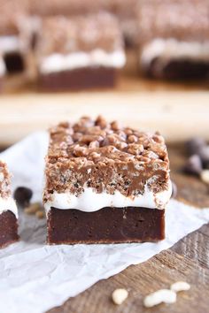 two pieces of chocolate dessert sitting on top of white parchment paper next to a cutting board