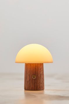 a mushroom shaped light sitting on top of a wooden table next to a white wall