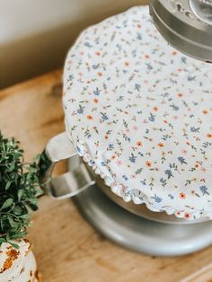 a close up of a cake on a stand with a flowered cloth covering it