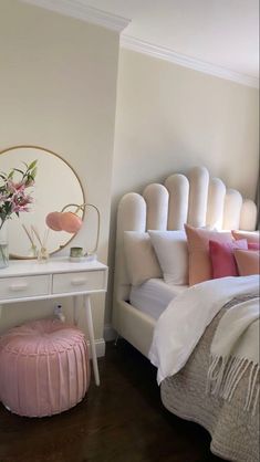 a white bed sitting next to a table with a mirror on it's side