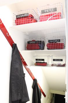 the closet is organized with red and white baskets