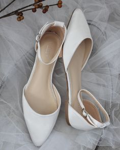 two pairs of white wedding shoes sitting on top of a bed