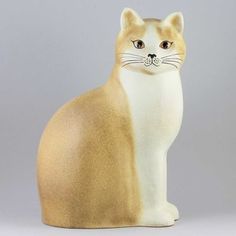 a cat figurine sitting on top of a white table next to a gray wall