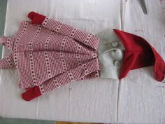 the doll is wearing a red and white checkered dress with matching hat on it